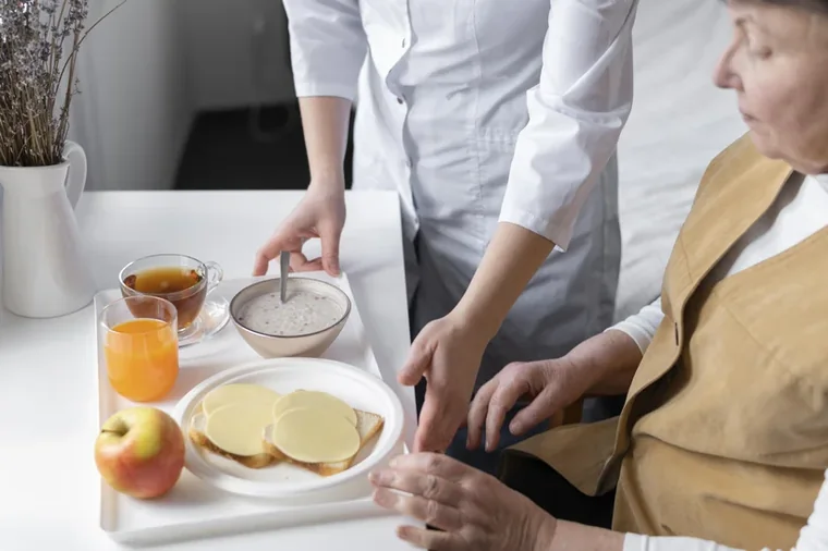 A caregiver gently helping a senior with a meal