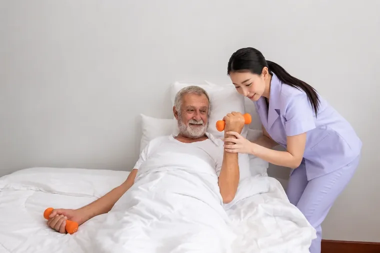 A caregiver guiding a senior man through gentle recovery exercises at home